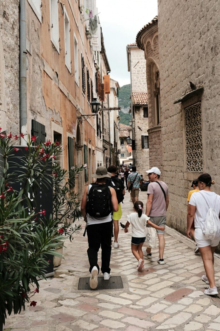 Tourists walk through cobblestone streets of Kotor, Montenegro, capturing an old town charm.