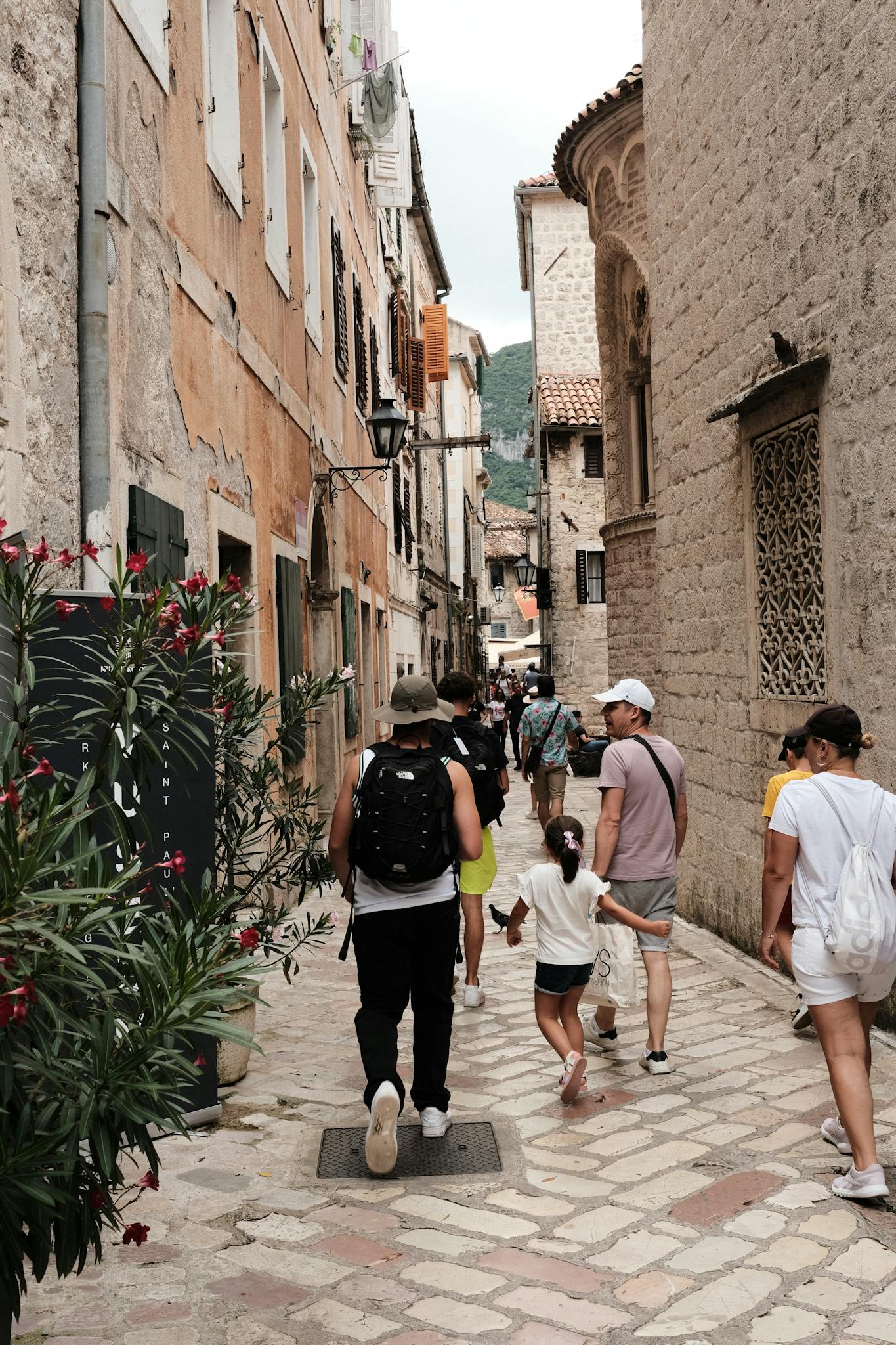 Tourists walk through cobblestone streets of Kotor, Montenegro, capturing an old town charm.