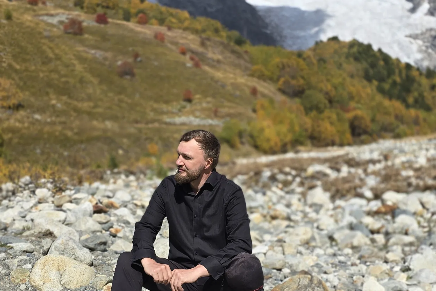 Wide glacial riverbed of grey stones below snow peaks in Upper Svaneti, Georgia