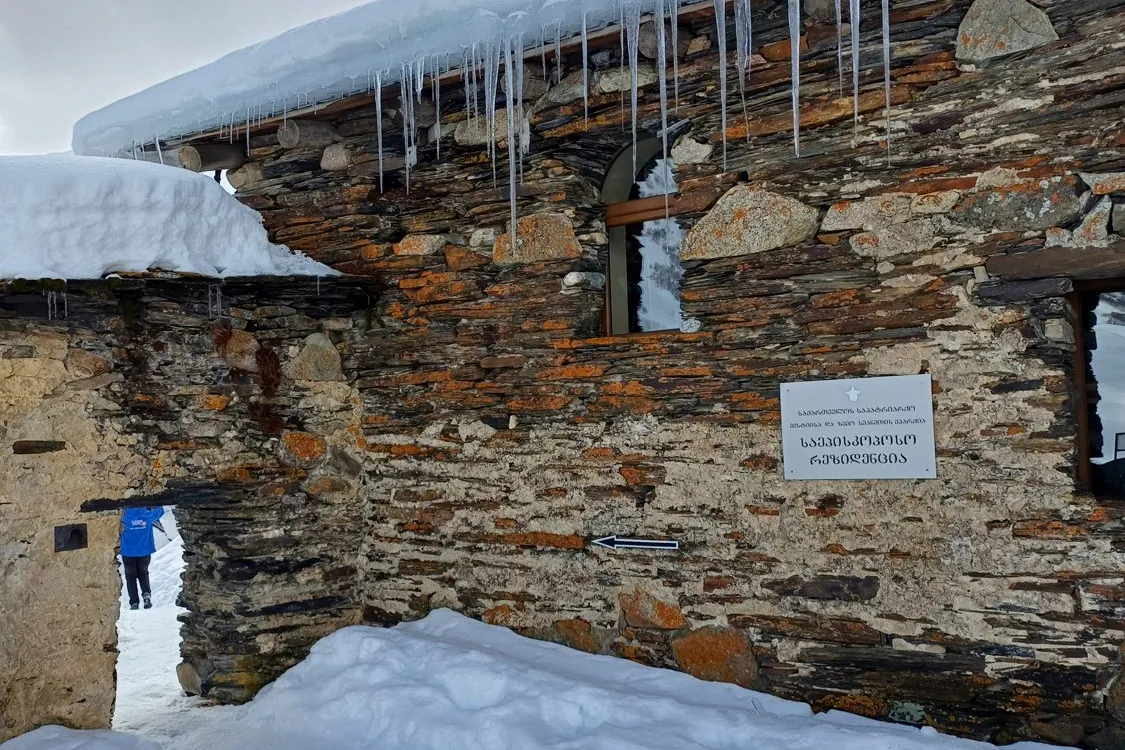 Icicles hanging from the stone roof of an old Svan house under deep winter snow, Georgia