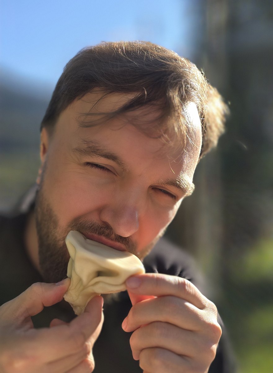 Jurijs, founder of Justvia, eating a fresh khinkali dumpling at a guesthouse table in Svaneti, Georgia
