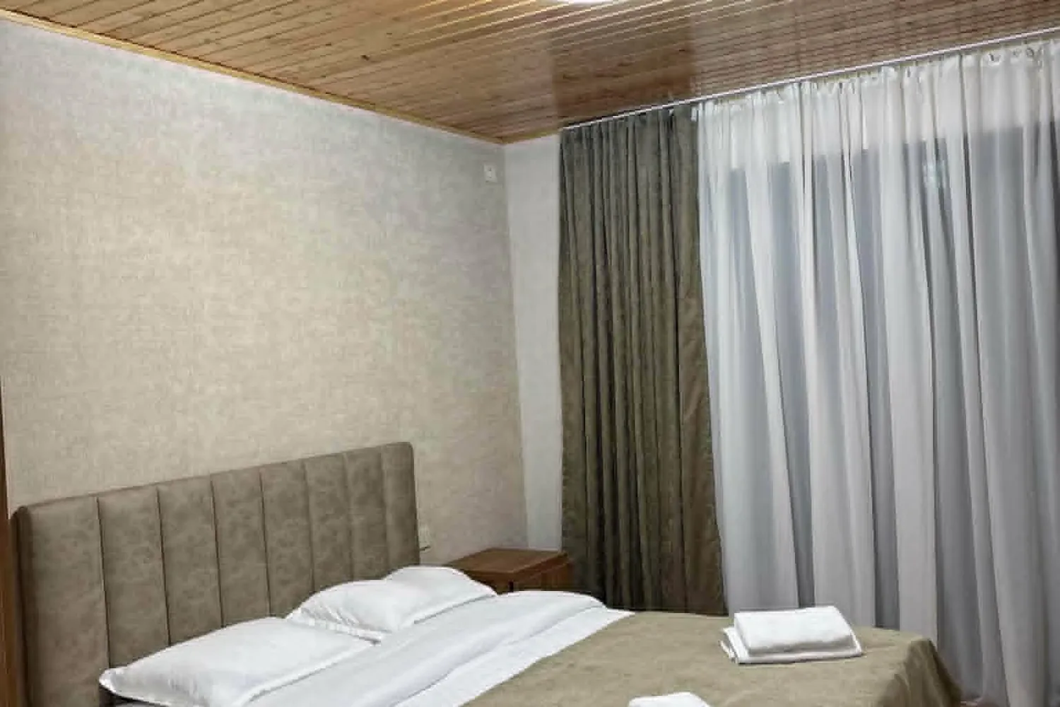 Family room with a double bed, wooden ceiling and window in a Mestia guesthouse, Svaneti, Georgia