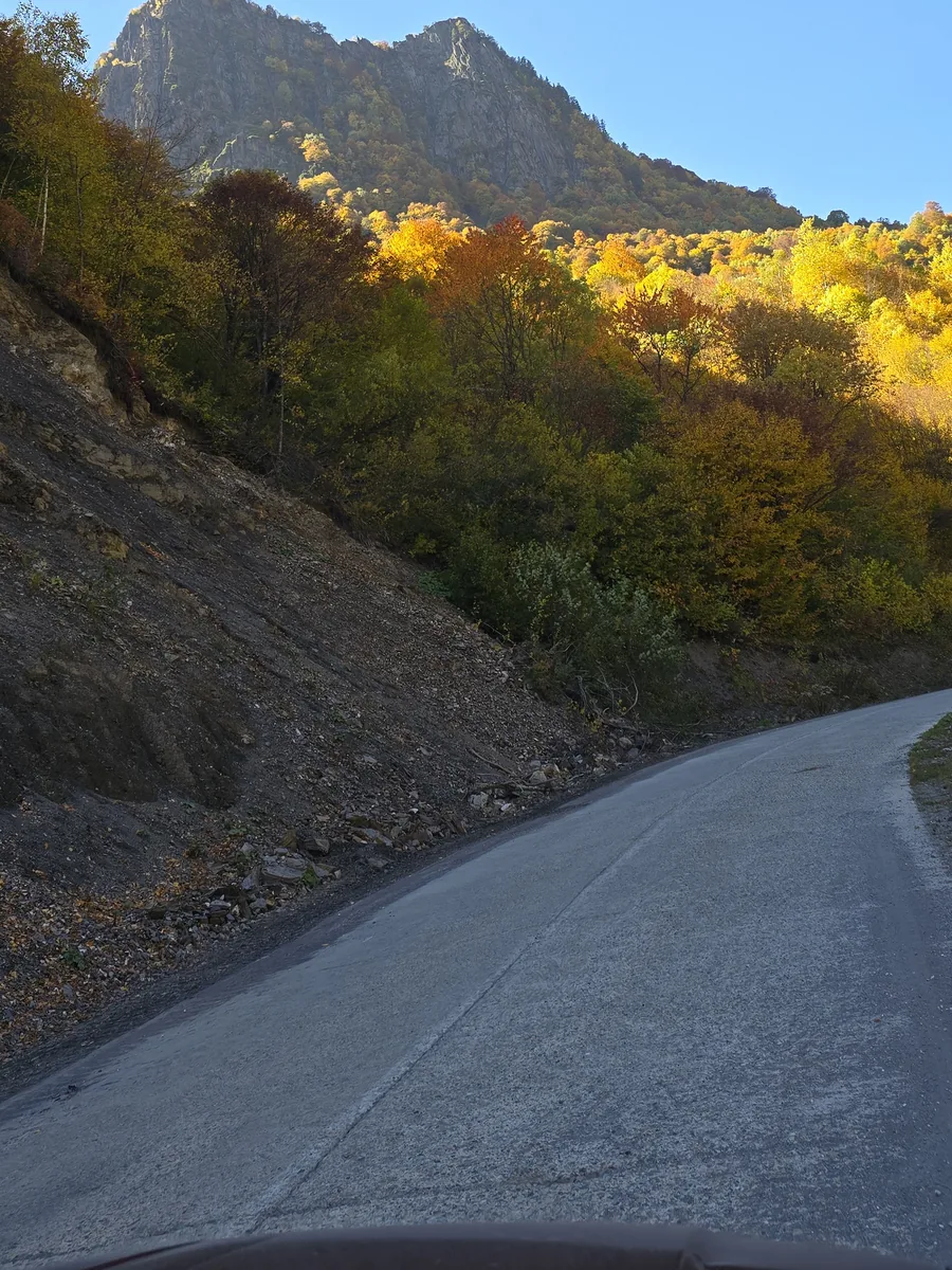 Sealed valley road climbing between autumn slopes and rock peaks in Upper Svaneti, Georgia