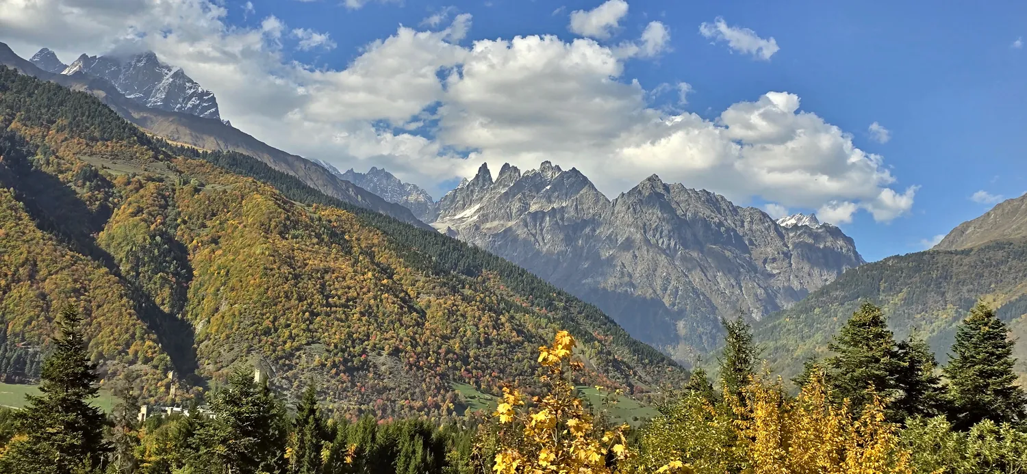 Jagged Caucasus peaks above autumn forest in Upper Svaneti, Georgia