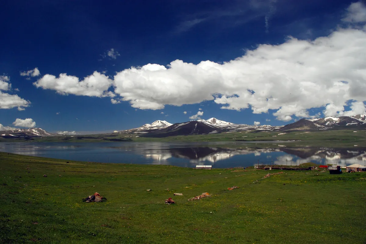 Lake Paravani with snow-topped hills reflected in the water under a blue sky, Georgia