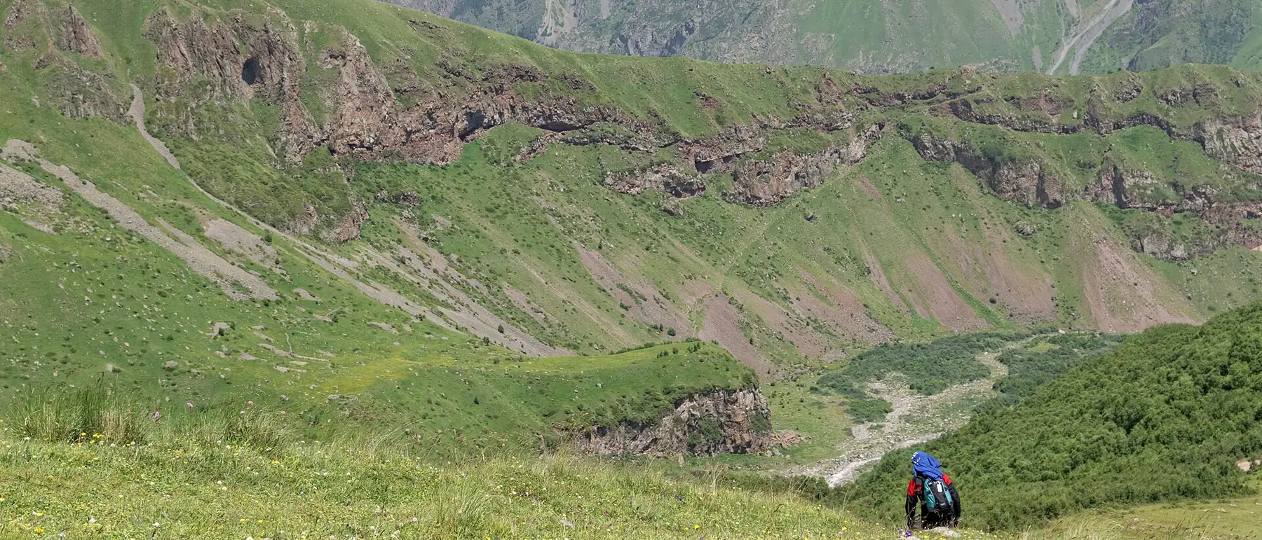 A walker on the green eastern slopes of Mount Kazbek, Georgia