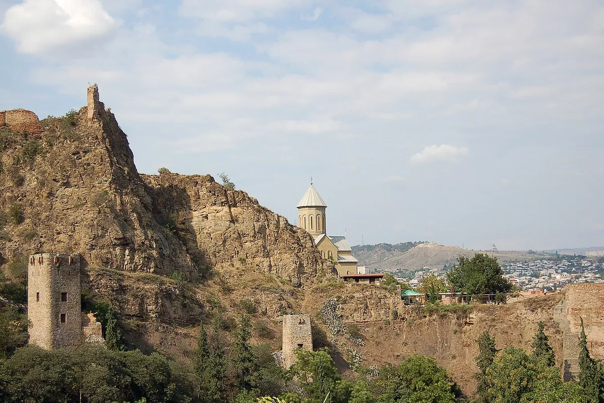 The ruined walls and towers of Narikala fortress on their rocky hill above Tbilisi, seen from the botanical garden, Georgia