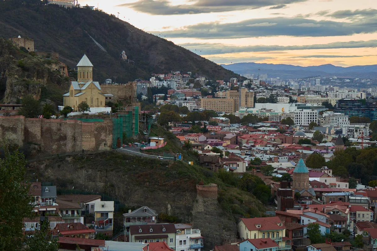The old town of Tbilisi in the evening light, with a church, red roofs and the hills above the city, Georgia