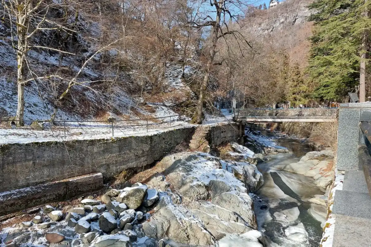 The Borjomula river running over stones through the Borjomi park in January, with light snow on the banks, Georgia