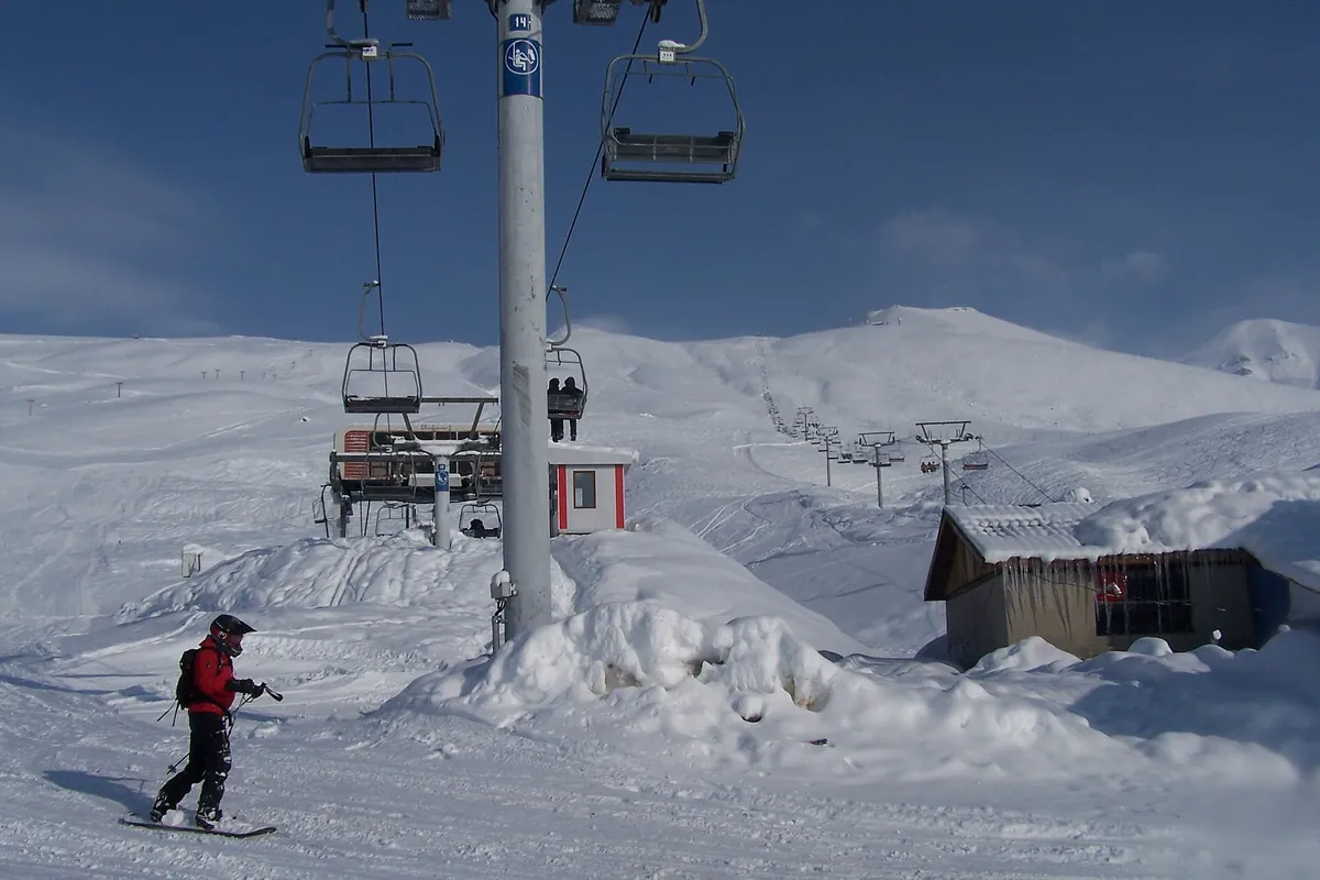 A snowboarder on a groomed slope beneath a chairlift at the Gudauri ski resort, Georgia